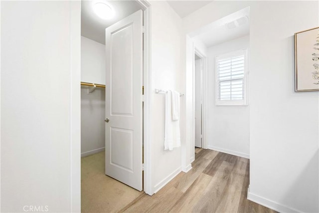 hall with light wood-style flooring and baseboards