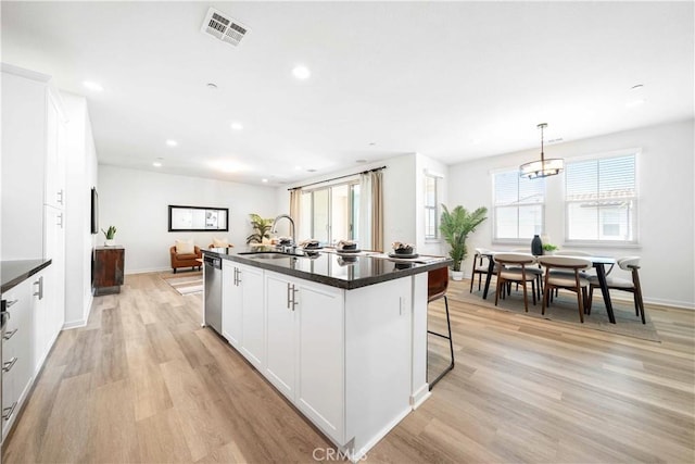 kitchen featuring a sink, dark countertops, stainless steel dishwasher, recessed lighting, and light wood finished floors