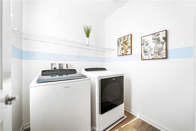 laundry area with washing machine and clothes dryer, wood finished floors, and baseboards