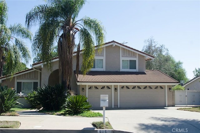 view of front of property featuring concrete driveway, a tile roof, a gate, fence, and stucco siding