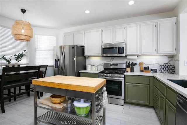 kitchen with white cabinets, hanging light fixtures, appliances with stainless steel finishes, open shelves, and green cabinetry