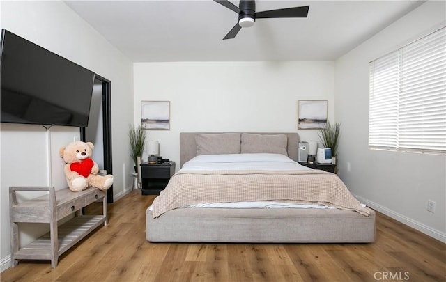 bedroom with light wood-type flooring, baseboards, and a ceiling fan