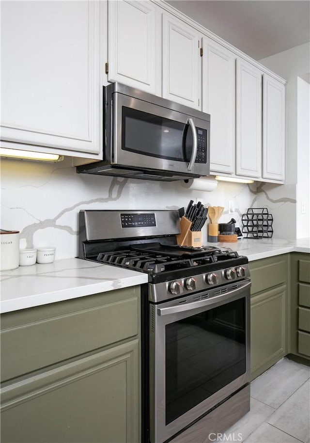 kitchen with appliances with stainless steel finishes, white cabinetry, and green cabinetry