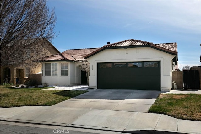 mediterranean / spanish home with driveway, a tile roof, an attached garage, fence, and stucco siding