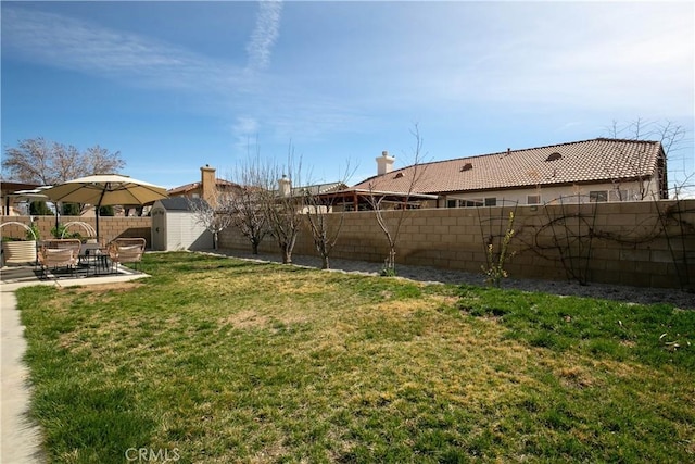 view of yard featuring a patio, a shed, an outdoor structure, and a fenced backyard