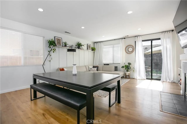 dining area featuring light wood finished floors, baseboards, visible vents, a fireplace, and recessed lighting