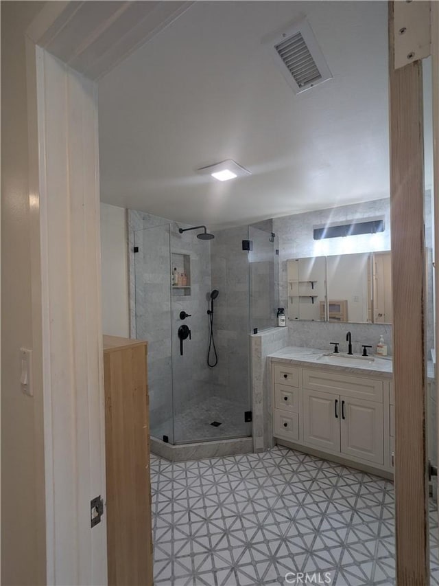 bathroom with a shower stall, visible vents, and vanity