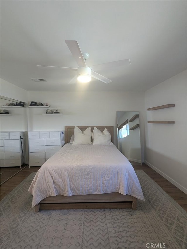 bedroom with baseboards, wood finished floors, visible vents, and a ceiling fan