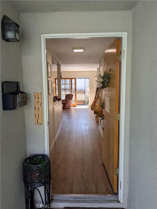 hall featuring wood finished floors and a textured wall