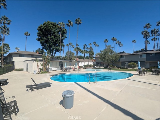 pool with a patio area, fence, and a hot tub