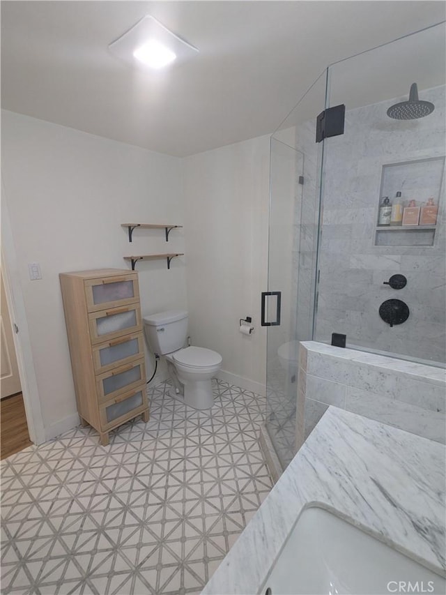 full bathroom with toilet, a shower stall, and baseboards