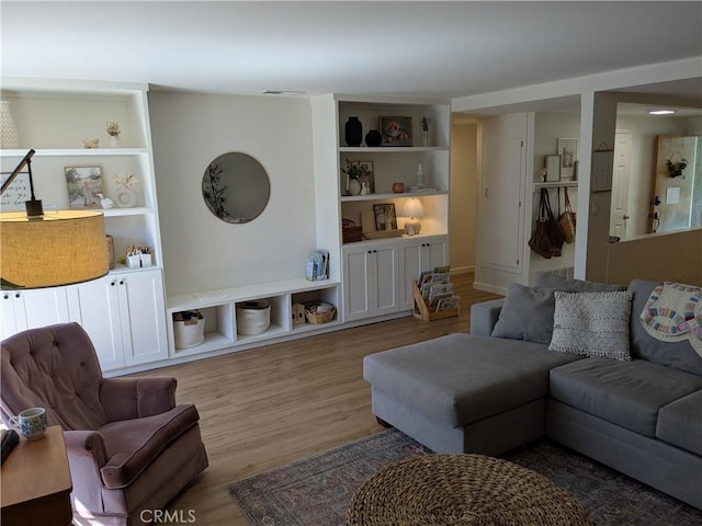 living area with built in shelves and wood finished floors