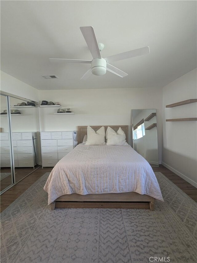 bedroom with a ceiling fan, baseboards, visible vents, and wood finished floors