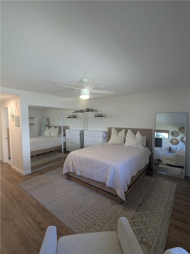 bedroom with ceiling fan, a closet, wood finished floors, and baseboards