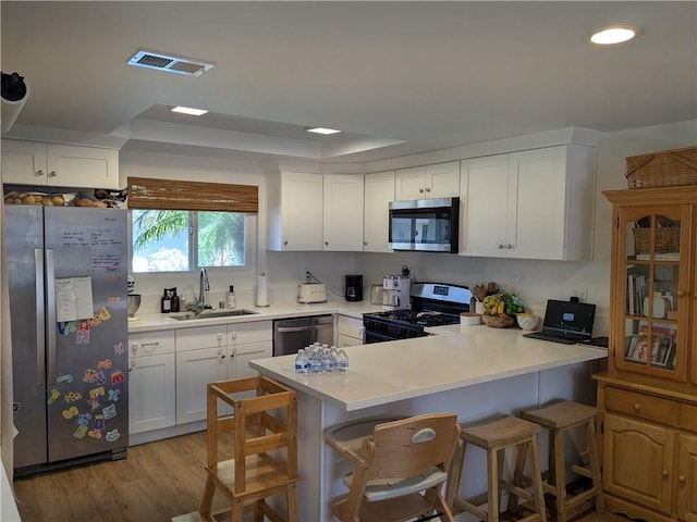 kitchen featuring a peninsula, a sink, visible vents, light countertops, and appliances with stainless steel finishes