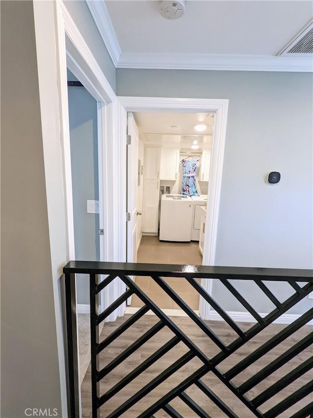 corridor featuring visible vents, ornamental molding, washing machine and dryer, an upstairs landing, and baseboards