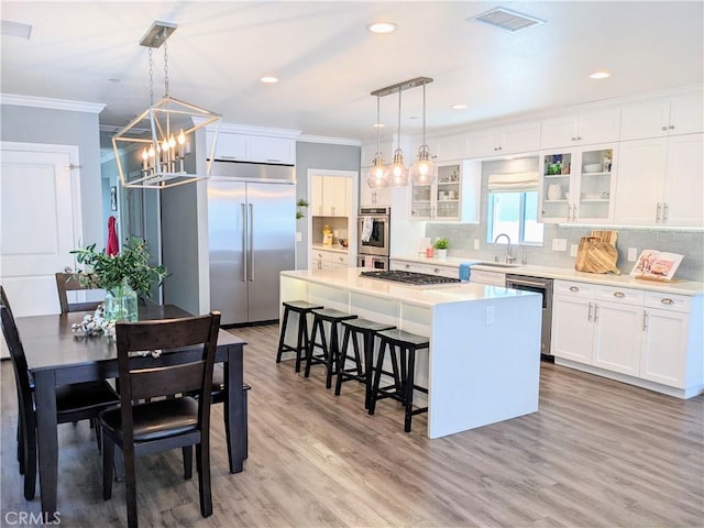 kitchen featuring crown molding, stainless steel appliances, visible vents, a sink, and a kitchen island