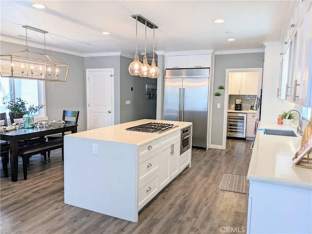 kitchen with wine cooler, crown molding, appliances with stainless steel finishes, white cabinetry, and a sink