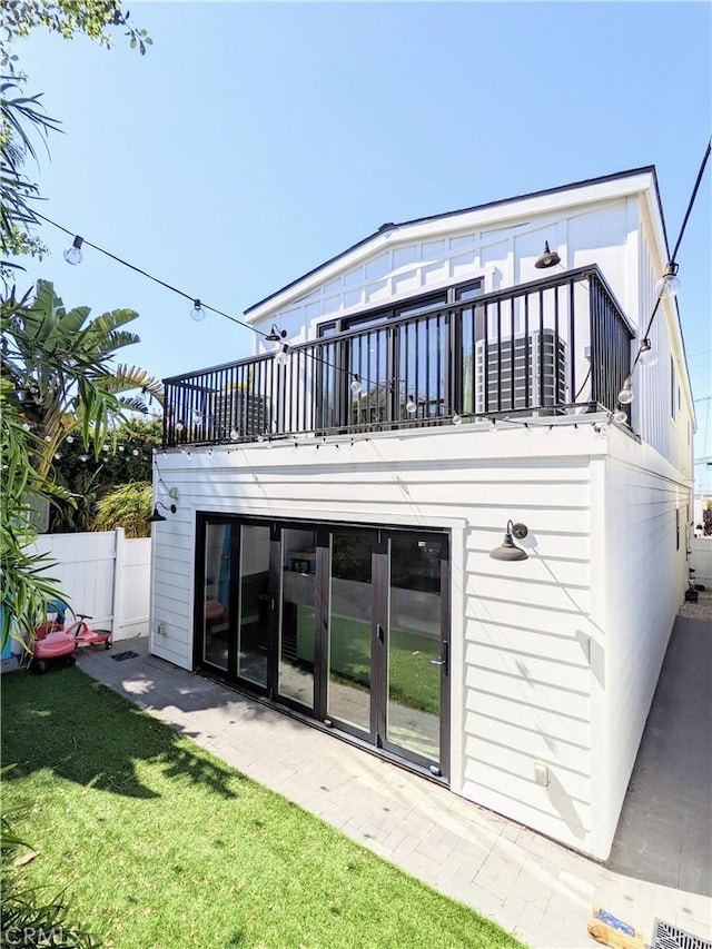 back of property featuring a yard, fence, and a balcony