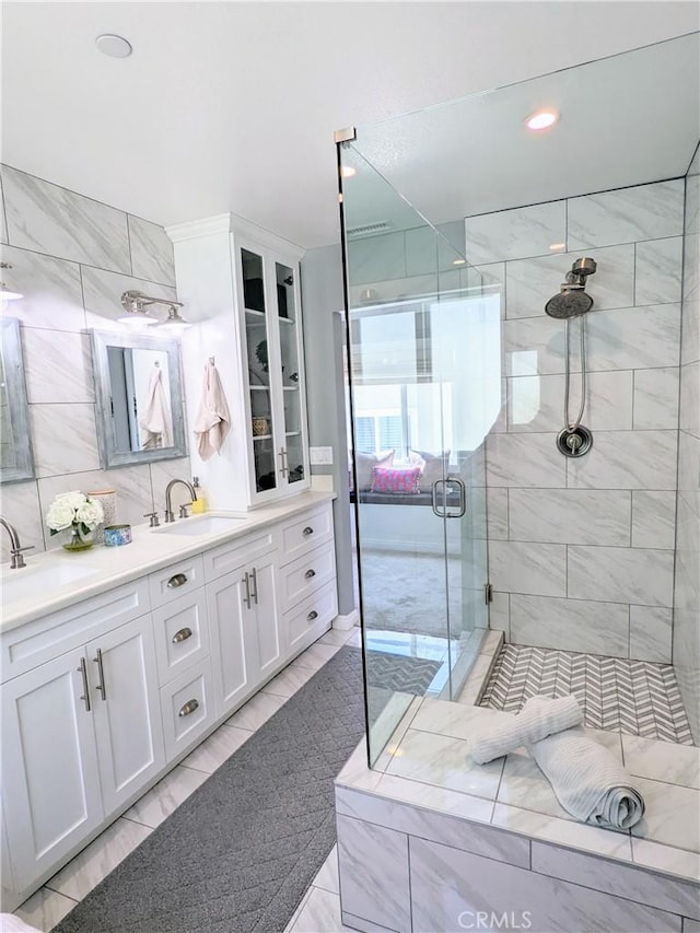 full bath featuring a sink, a shower stall, decorative backsplash, and double vanity