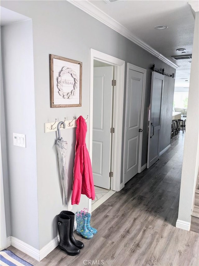 mudroom featuring ornamental molding, a barn door, wood finished floors, and baseboards