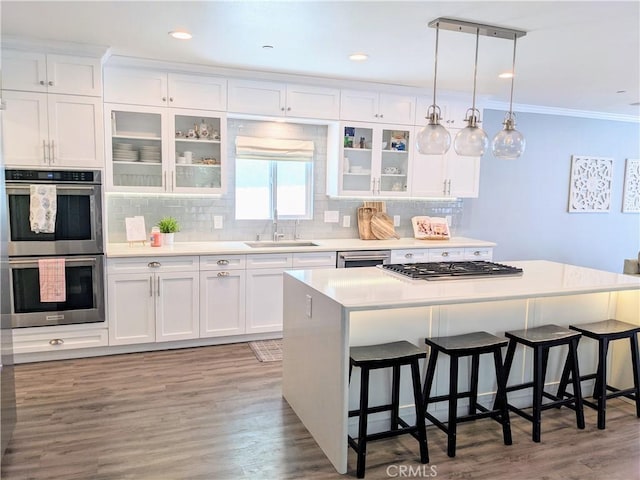 kitchen featuring a breakfast bar area, stainless steel appliances, a kitchen island, a sink, and white cabinets