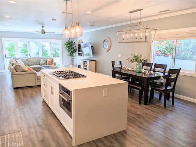 kitchen with stainless steel appliances, a healthy amount of sunlight, wood finished floors, and crown molding