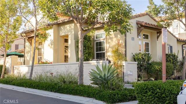 view of property exterior featuring a fenced front yard, a tile roof, and stucco siding