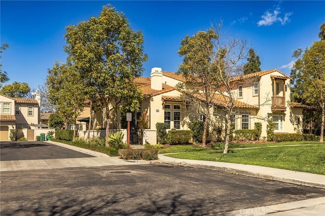 mediterranean / spanish-style home with a tile roof, fence, a residential view, and a front yard