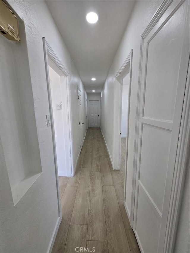 hallway with recessed lighting, light wood-style flooring, and baseboards