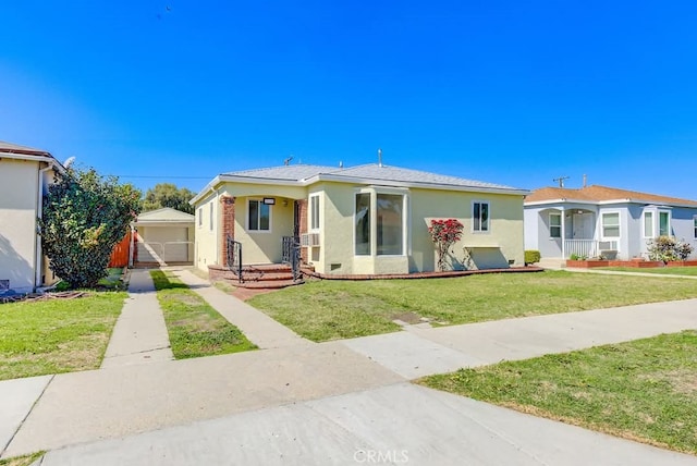 bungalow with a front yard, an outdoor structure, concrete driveway, and stucco siding