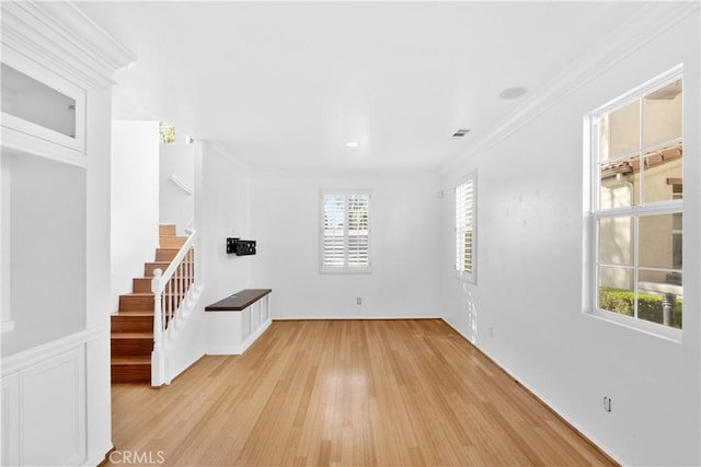 unfurnished room featuring crown molding, light wood-style flooring, and stairs