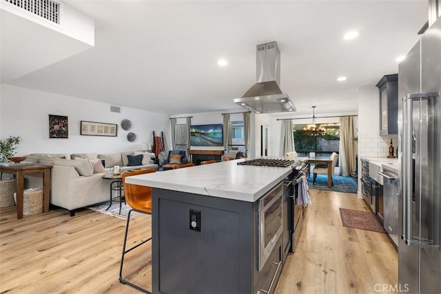 kitchen featuring range hood, a breakfast bar area, stainless steel appliances, and light countertops