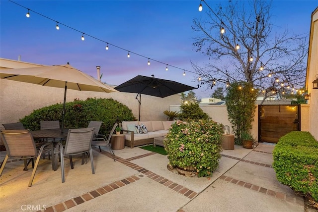 patio terrace at dusk featuring outdoor dining space, fence, and an outdoor living space