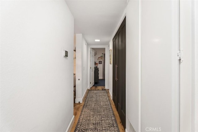 hallway featuring light wood finished floors and baseboards