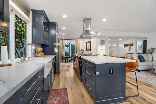 kitchen featuring light wood finished floors, a kitchen island, open floor plan, island exhaust hood, and stainless steel range with gas stovetop