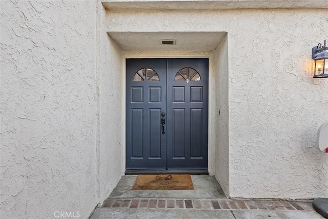 entrance to property featuring stucco siding