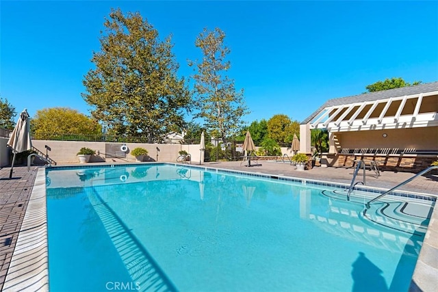 pool with a patio area and fence