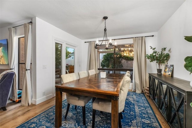 dining space featuring baseboards, wood finished floors, and an inviting chandelier