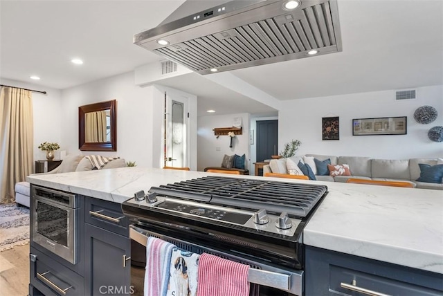 kitchen featuring stainless steel gas range oven, visible vents, wall chimney exhaust hood, open floor plan, and wood finished floors