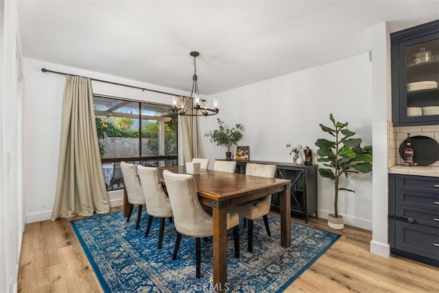 dining area featuring light wood finished floors, baseboards, and a chandelier