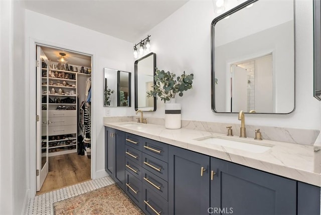 full bath with double vanity, a sink, and a walk in closet