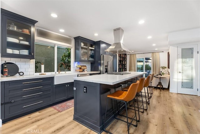 kitchen featuring light countertops, light wood-style floors, a sink, and island range hood