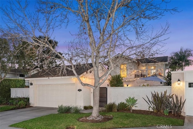 view of front of house featuring a garage, driveway, fence, and stucco siding