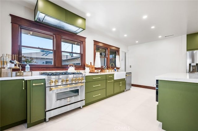 kitchen featuring green cabinets, light countertops, appliances with stainless steel finishes, and a sink