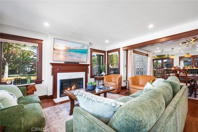 living area with a fireplace with flush hearth, plenty of natural light, and wood finished floors