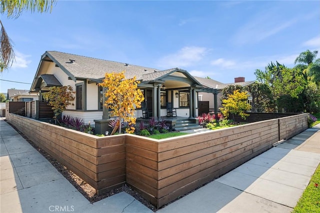 view of front of house with a fenced front yard and roof with shingles