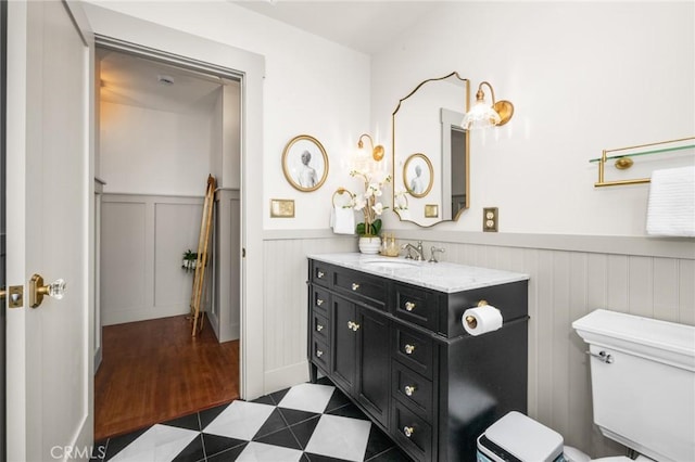 bathroom with toilet, vanity, and wainscoting