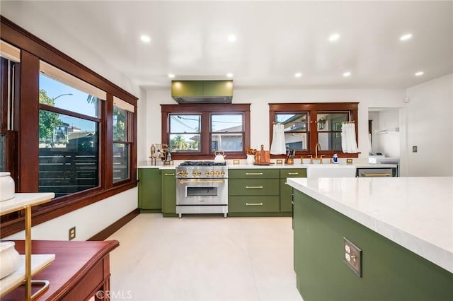 kitchen featuring light countertops, stainless steel range, a sink, and green cabinetry