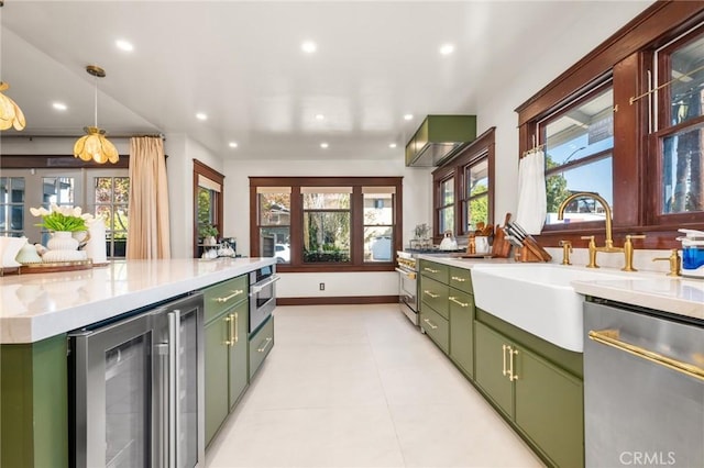 kitchen featuring wine cooler, stainless steel appliances, light countertops, green cabinets, and a sink